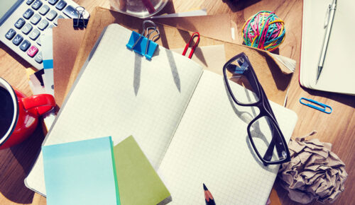 Desk workspace with open notebook and glasses