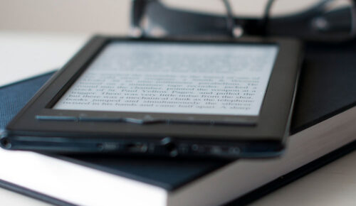 E-reader on book with reading glasses