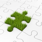 Green grass puzzle piece in white jigsaw